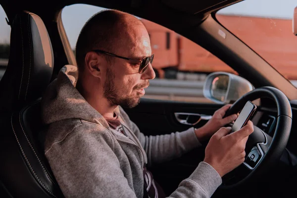 Güneş Gözlüklü Bir Adam Araba Kullanıyor Gün Batımında Akıllı Telefondan — Stok fotoğraf
