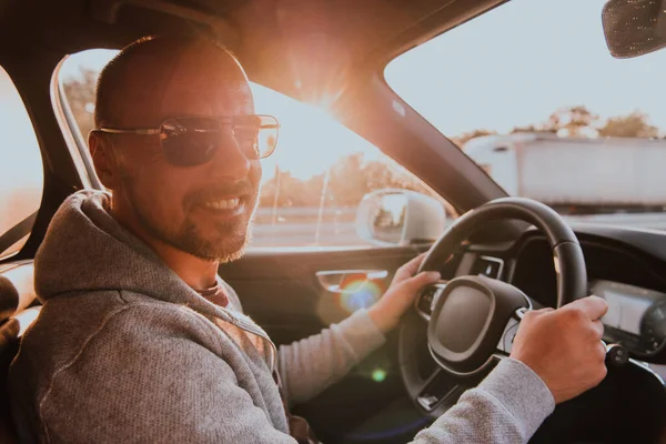 一个戴着太阳镜的男人在日落时开车 汽车旅行的概念 — 图库照片