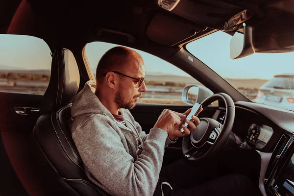 Ein Mann Mit Sonnenbrille Fährt Auto Und Tippt Bei Sonnenuntergang — Stockfoto