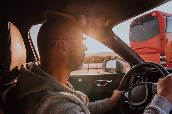 日没時にサングラスをかけた男が車を運転している 車旅行の概念 — ストック写真