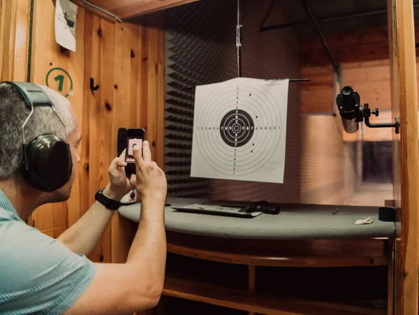 A man in a shooting range takes a picture and examines the results after shooting. High quality photo