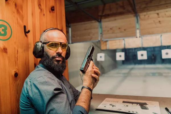 一名男子戴着防护耳机 在射击场练习射击手枪 — 图库照片
