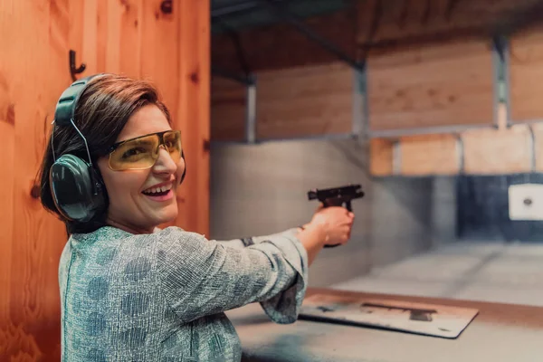 Kobieta Ćwiczy Strzelanie Pistoletu Strzelnicy Nosząc Słuchawki Ochronne — Zdjęcie stockowe