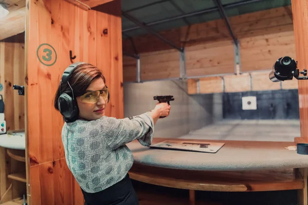 一名妇女戴着防护耳机 在射击场练习射击手枪 — 图库照片