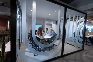 Bir grup genç girişimci odaklanmış bir toplantıya katılıyor, çeşitli iş stratejilerini tartışıyor ve işbirliği içinde zorlu sorunları çözüyorlar, hırslarını, yaratıcılıklarını ve