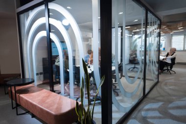 Bir grup genç girişimci odaklanmış bir toplantıya katılıyor, çeşitli iş stratejilerini tartışıyor ve işbirliği içinde zorlu sorunları çözüyorlar, hırslarını, yaratıcılıklarını ve