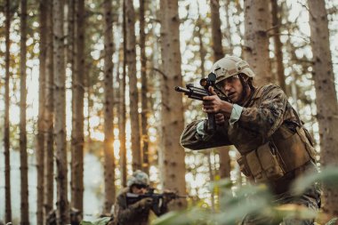 Bir grup modern savaş askeri tehlikeli uzak orman bölgelerinde savaşıyor. Bir grup asker modern silahlarla düşman hattında savaşıyor. Savaş ve askerlik kavramı.