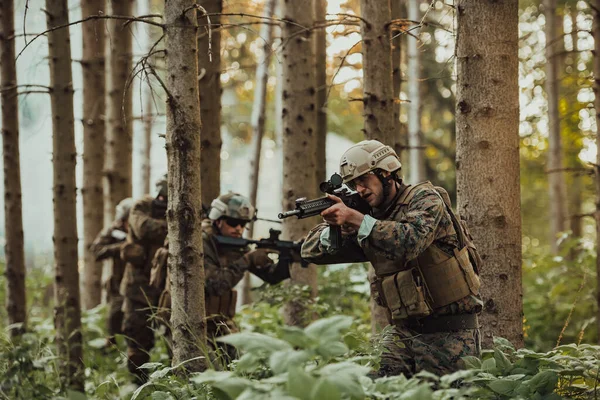 A group of modern warfare soldiers is fighting a war in dangerous remote forest areas. A group of soldiers is fighting on the enemy line with modern weapons. The concept of warfare and military