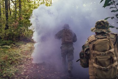 Bir grup modern savaş askeri tehlikeli uzak orman bölgelerinde savaşıyor. Bir grup asker modern silahlarla düşman hattında savaşıyor. Savaş ve askerlik kavramı.