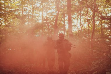 Bir grup modern savaş askeri tehlikeli uzak orman bölgelerinde savaşıyor. Bir grup asker modern silahlarla düşman hattında savaşıyor. Savaş ve askerlik kavramı.