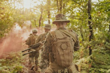 Bir grup modern savaş askeri tehlikeli uzak orman bölgelerinde savaşıyor. Bir grup asker modern silahlarla düşman hattında savaşıyor. Savaş ve askerlik kavramı.