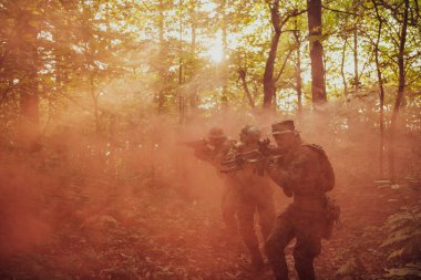 Bir grup modern savaş askeri tehlikeli uzak orman bölgelerinde savaşıyor. Bir grup asker modern silahlarla düşman hattında savaşıyor. Savaş ve askerlik kavramı.