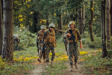 Bir grup modern savaş askeri tehlikeli uzak orman bölgelerinde savaşıyor. Bir grup asker modern silahlarla düşman hattında savaşıyor. Savaş ve askerlik kavramı.