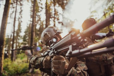 Bir grup modern savaş askeri tehlikeli uzak orman bölgelerinde savaşıyor. Bir grup asker modern silahlarla düşman hattında savaşıyor. Savaş ve askerlik kavramı.
