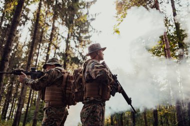 Bir grup modern savaş askeri tehlikeli uzak orman bölgelerinde savaşıyor. Bir grup asker modern silahlarla düşman hattında savaşıyor. Savaş ve askerlik kavramı.