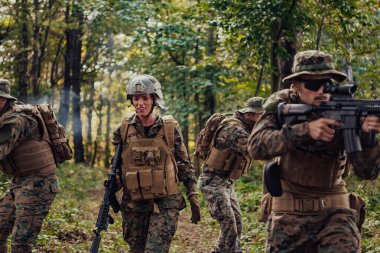 Bir grup modern savaş askeri tehlikeli uzak orman bölgelerinde savaşıyor. Bir grup asker modern silahlarla düşman hattında savaşıyor. Savaş ve askerlik kavramı.