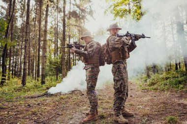 Bir grup modern savaş askeri tehlikeli uzak orman bölgelerinde savaşıyor. Bir grup asker modern silahlarla düşman hattında savaşıyor. Savaş ve askerlik kavramı.