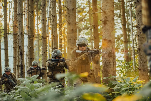 A group of modern warfare soldiers is fighting a war in dangerous remote forest areas. A group of soldiers is fighting on the enemy line with modern weapons. The concept of warfare and military