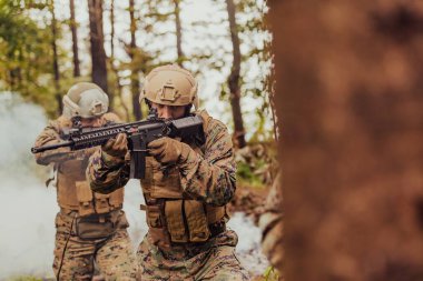 Bir grup modern savaş askeri tehlikeli uzak orman bölgelerinde savaşıyor. Bir grup asker modern silahlarla düşman hattında savaşıyor. Savaş ve askerlik kavramı.