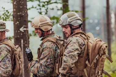 Bir grup modern savaş askeri tehlikeli uzak orman bölgelerinde savaşıyor. Bir grup asker modern silahlarla düşman hattında savaşıyor. Savaş ve askerlik kavramı.