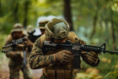 Bir grup modern savaş askeri tehlikeli uzak orman bölgelerinde savaşıyor. Bir grup asker modern silahlarla düşman hattında savaşıyor. Savaş ve askerlik kavramı.