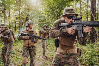 Bir grup modern savaş askeri tehlikeli uzak orman bölgelerinde savaşıyor. Bir grup asker modern silahlarla düşman hattında savaşıyor. Savaş ve askerlik kavramı.