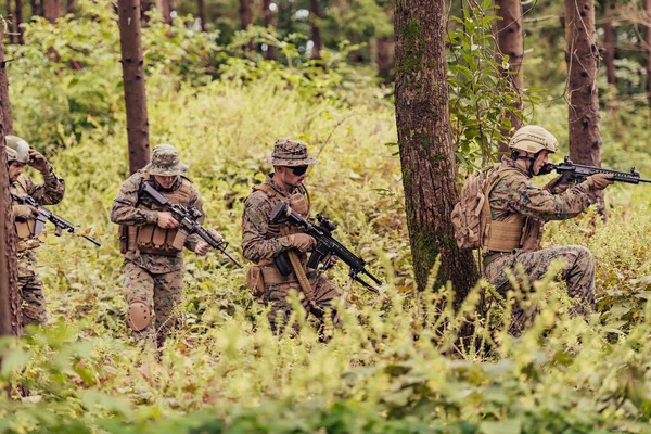 現代の戦争兵士のグループは危険な人里離れた森林地帯で戦争を戦っています 現代の武器で敵陣で戦っている兵士のグループ 戦争と軍事の概念 — ストック写真