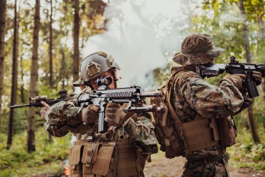 Bir grup modern savaş askeri tehlikeli uzak orman bölgelerinde savaşıyor. Bir grup asker modern silahlarla düşman hattında savaşıyor. Savaş ve askerlik kavramı.