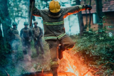 İtfaiyeci kahraman, yangın ateşinin üzerinden atlayıp kurtarma tehlikesiyle karşı karşıya..