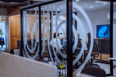 Bir grup genç girişimci odaklanmış bir toplantıya katılıyor, çeşitli iş stratejilerini tartışıyor ve işbirliği içinde zorlu sorunları çözüyorlar, hırslarını, yaratıcılıklarını ve