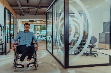 Büyük, modern bir şirkette, tekerlekli sandalyedeki kararlı bir işadamı bir koridorda dolaşır, kurumsal dünyaya güç ve kapsayıcılık kazandırır.