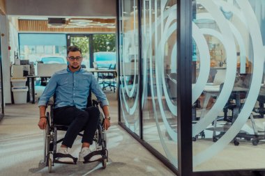 Büyük, modern bir şirkette, tekerlekli sandalyedeki kararlı bir işadamı bir koridorda dolaşır, kurumsal dünyaya güç ve kapsayıcılık kazandırır.