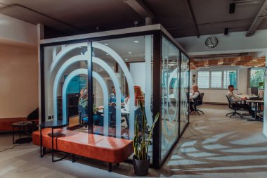 Bir grup genç girişimci odaklanmış bir toplantıya katılıyor, çeşitli iş stratejilerini tartışıyor ve işbirliği içinde zorlu sorunları çözüyorlar, hırslarını, yaratıcılıklarını ve