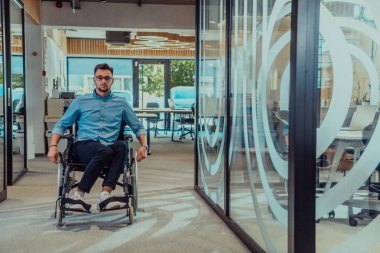 Büyük, modern bir şirkette, tekerlekli sandalyedeki kararlı bir işadamı bir koridorda dolaşır, kurumsal dünyaya güç ve kapsayıcılık kazandırır.