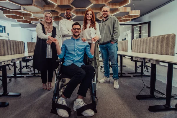 近代的なオフィスの若いビジネスマンは 車椅子で彼らのビジネス同僚に握手を拡大し 企業環境における包括性 サポート 団結を示しています — ストック写真