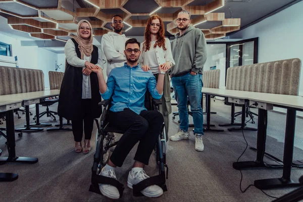 近代的なオフィスの若いビジネスマンは 車椅子で彼らのビジネス同僚に握手を拡大し 企業環境における包括性 サポート 団結を示しています — ストック写真