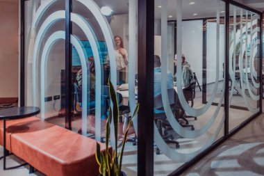 Bir grup genç girişimci odaklanmış bir toplantıya katılıyor, çeşitli iş stratejilerini tartışıyor ve işbirliği içinde zorlu sorunları çözüyorlar, hırslarını, yaratıcılıklarını ve