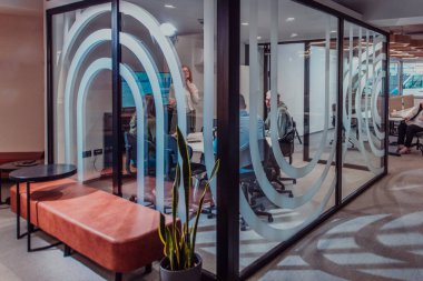 Bir grup genç girişimci odaklanmış bir toplantıya katılıyor, çeşitli iş stratejilerini tartışıyor ve işbirliği içinde zorlu sorunları çözüyorlar, hırslarını, yaratıcılıklarını ve