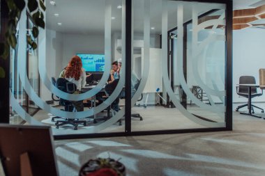 Bir grup genç girişimci odaklanmış bir toplantıya katılıyor, çeşitli iş stratejilerini tartışıyor ve işbirliği içinde zorlu sorunları çözüyorlar, hırslarını, yaratıcılıklarını ve