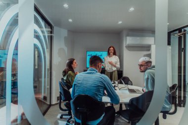 Bir grup genç girişimci odaklanmış bir toplantıya katılıyor, çeşitli iş stratejilerini tartışıyor ve işbirliği içinde zorlu sorunları çözüyorlar, hırslarını, yaratıcılıklarını ve