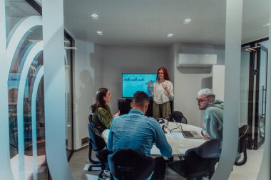 Bir grup genç girişimci odaklanmış bir toplantıya katılıyor, çeşitli iş stratejilerini tartışıyor ve işbirliği içinde zorlu sorunları çözüyorlar, hırslarını, yaratıcılıklarını ve