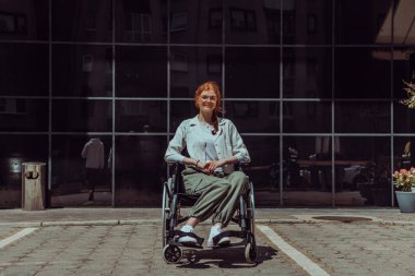 Modern bir şirket binasının önünde, tekerlekli sandalyede kendinden emin bir şekilde oturan genç bir kadın, güçlendirmeyi, kapsayıcılığı ve iş dünyasındaki zorlukların üstesinden gelme gücünü simgeliyor.. 