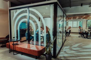 Bir grup genç girişimci odaklanmış bir toplantıya katılıyor, çeşitli iş stratejilerini tartışıyor ve işbirliği içinde zorlu sorunları çözüyorlar, hırslarını, yaratıcılıklarını ve