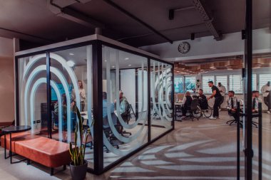 Modern bir ofiste, profesyonel bir videograf ekibi, bir grup genç girişimciyi filme çekerken yaratıcılığın ve yeniliğin özünü yakalar ve işbirliğini ve hırsını sembolize eder.