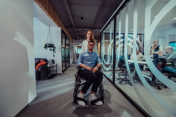 年轻的商业伙伴 合作的商业伙伴 包括坐在轮椅上的人 走过了现代玻璃办公室走廊 展示了现代社会的多样性 团队精神和赋权 — 图库照片