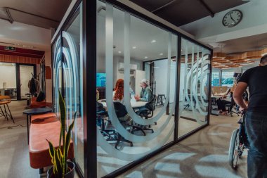 Bir grup genç girişimci odaklanmış bir toplantıya katılıyor, çeşitli iş stratejilerini tartışıyor ve işbirliği içinde zorlu sorunları çözüyorlar, hırslarını, yaratıcılıklarını ve