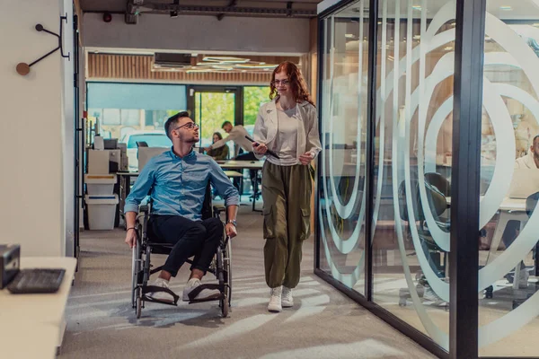 年轻的商业伙伴 合作的商业伙伴 包括坐在轮椅上的人 走过了现代玻璃办公室走廊 展示了现代社会的多样性 团队精神和赋权 — 图库照片