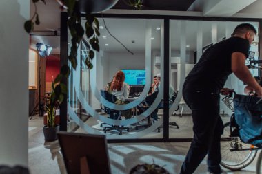 Modern bir ofiste, profesyonel bir videograf ekibi, bir grup genç girişimciyi filme çekerken yaratıcılığın ve yeniliğin özünü yakalar ve işbirliğini ve hırsını sembolize eder.