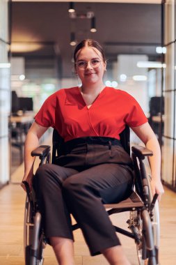 Tekerlekli sandalyedeki modern genç bir iş kadını cam duvarlı ofisleri olan, iş dünyasındaki azim ve yenilikleri somutlaştıran, kapsamlı bir çalışma alanıyla çevrilidir..