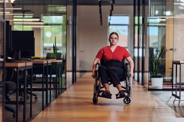 一个坐在轮椅上的现代女商人被一个有玻璃墙办公室的包容性工作空间所围绕 体现了商界的决心和创新精神 — 图库照片